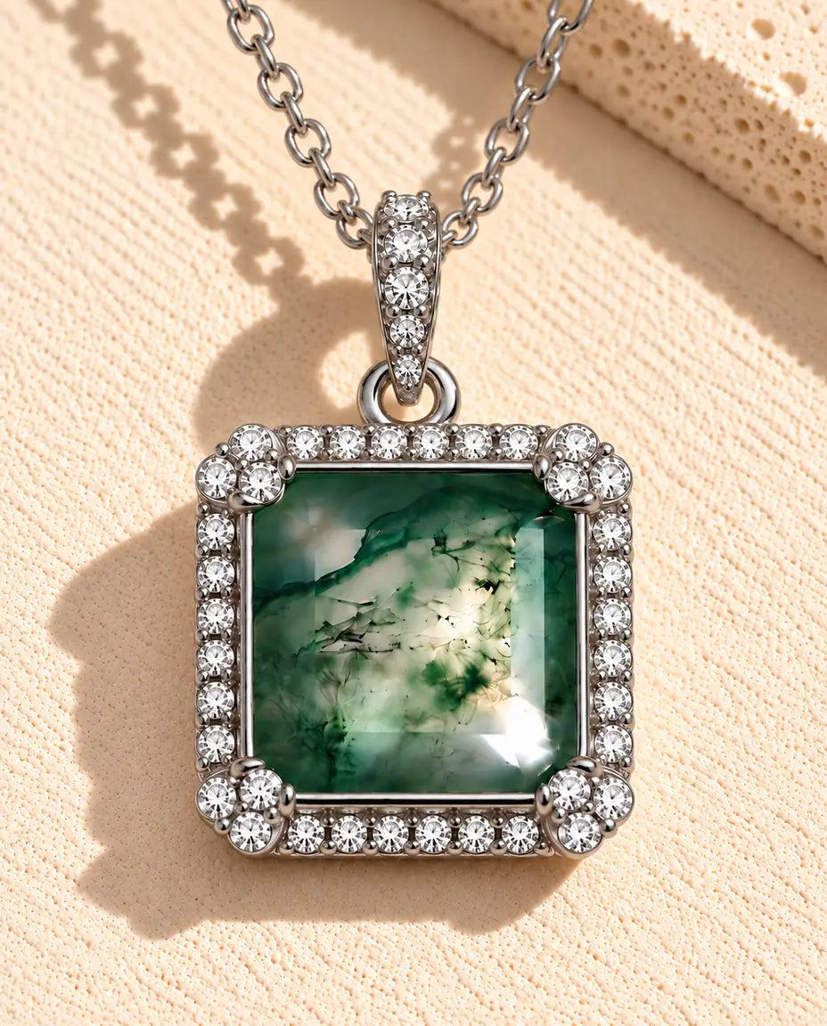 Collier Agate Mousse Carrée en Argent 925 - posé sur une surface claire texturée près d’un bloc de travertin