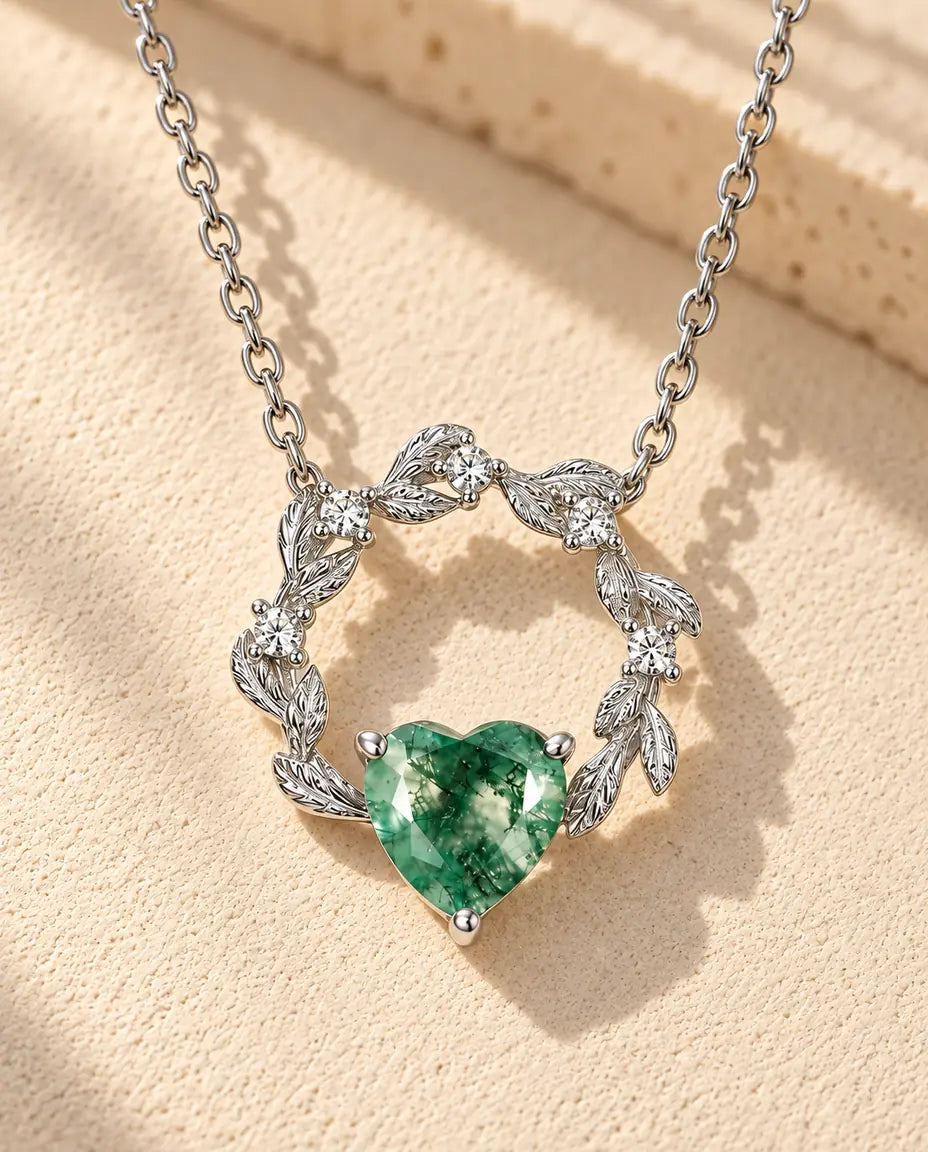 Collier Cœur Agate Mousse en Argent 925 - posé sur une surface claire texturée près d’un bloc de travertin