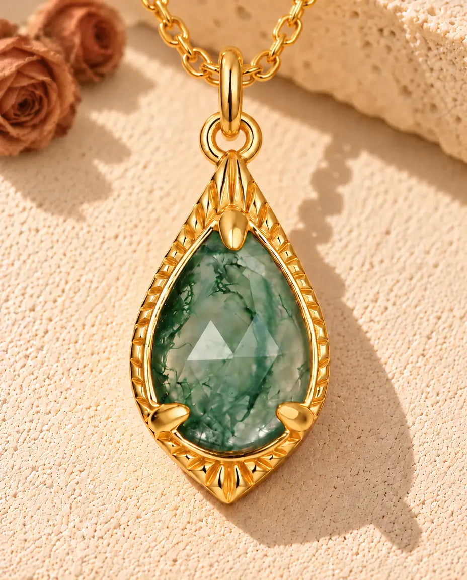 Collier Agate Mousse Goutte en Argent 925 Plaqué Or - posé sur une surface claire texturée près d’un bloc de travertin
