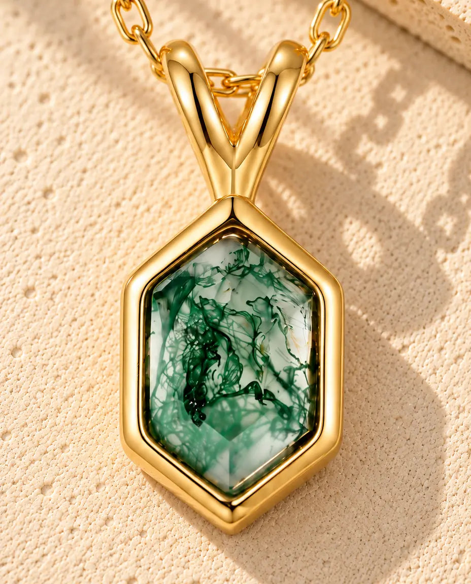 Collier Agate Mousse Hexagonale en Argent 925 Plaqué Or - posé sur une surface claire texturée près d’un bloc de travertin