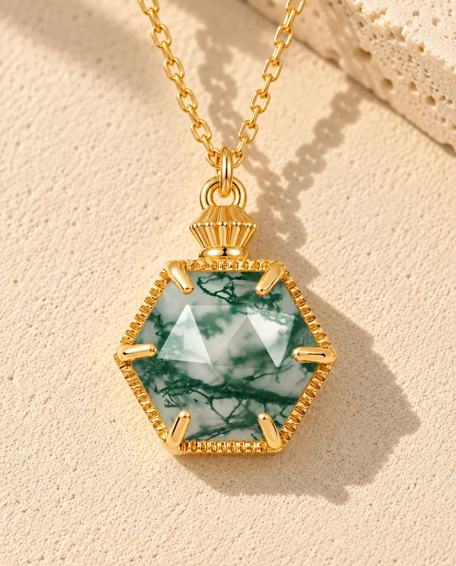 Collier Agate Mousse Hexagonale en Argent 925 Plaqué Or - posé sur une surface claire texturée près d’un bloc de travertin
