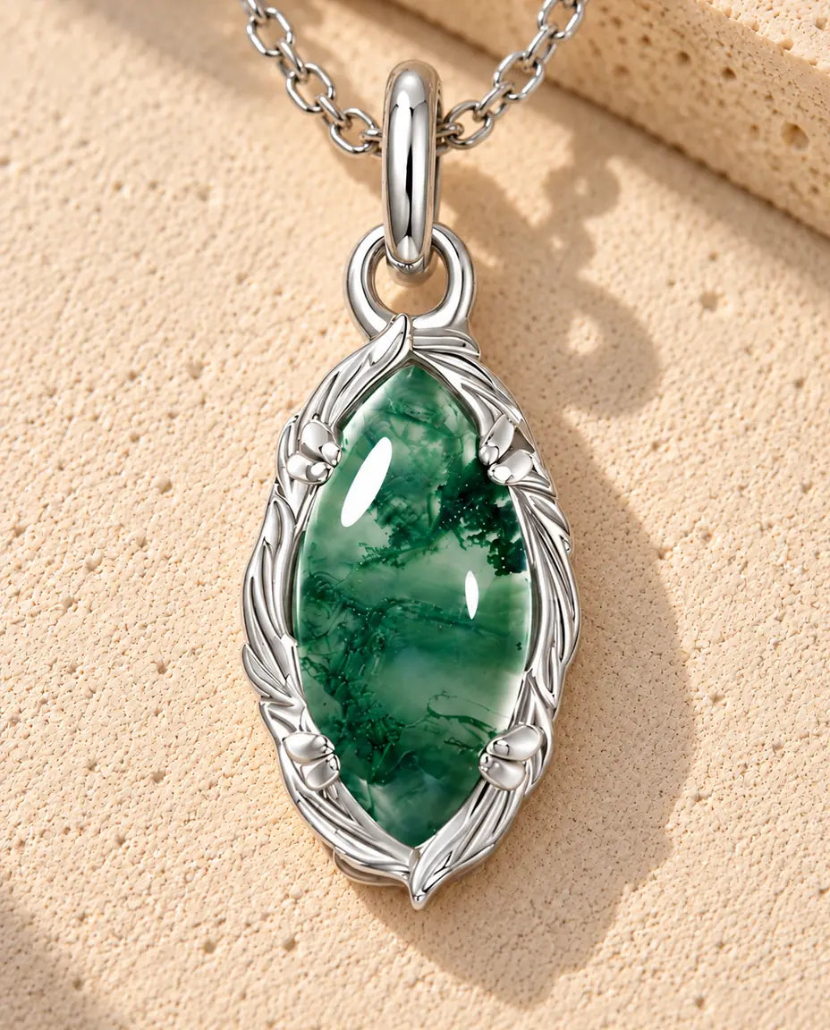 Collier Agate Mousse Marquise en Argent 925 - posé sur une surface claire texturée près d’un bloc de travertin