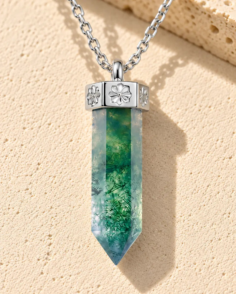 Collier Agate Mousse Pointe en Argent 925 - posé sur une surface claire texturée près d’un bloc de travertin