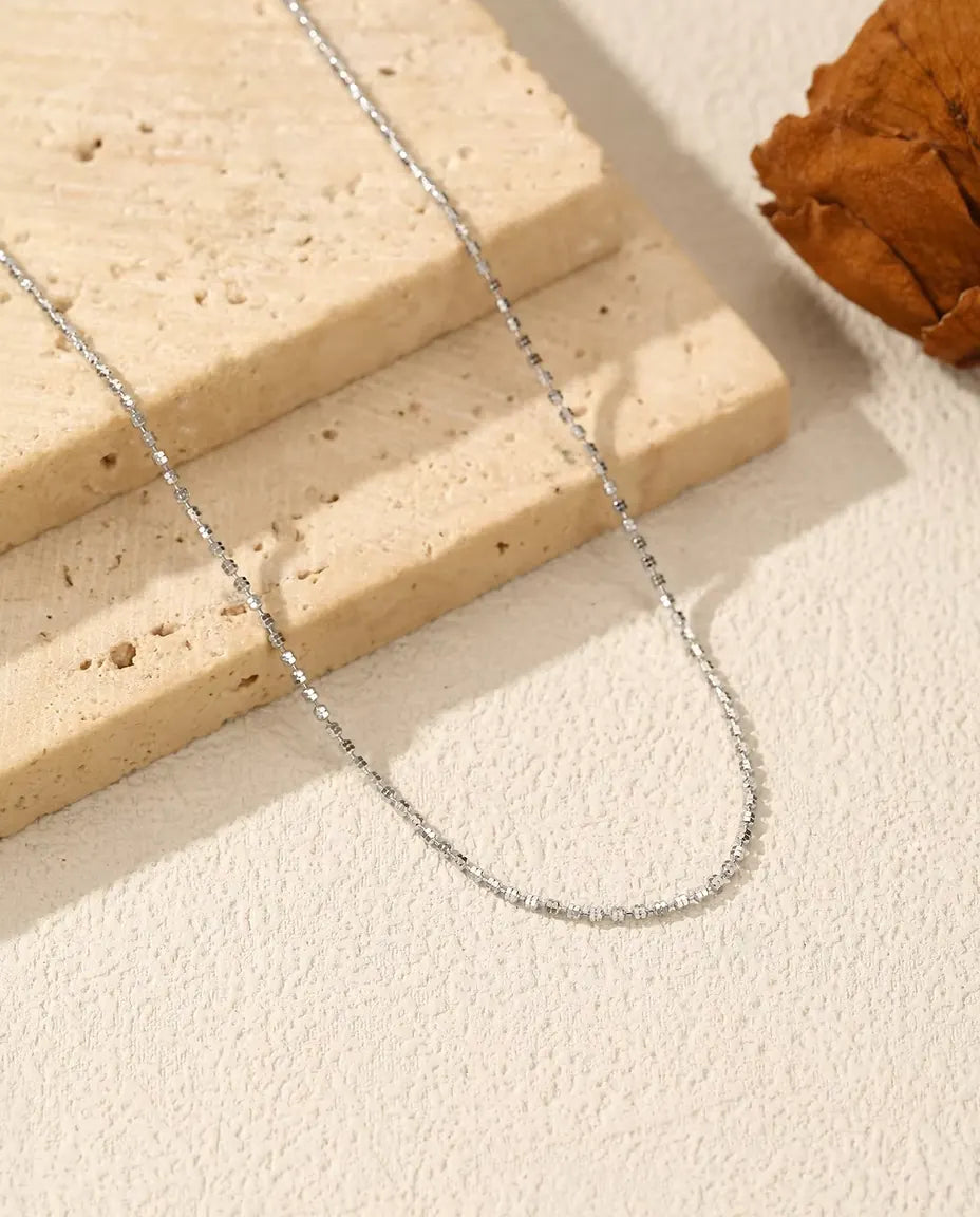 Collier Chaîne Diamantée en Argent 925 - posé sur une surface claire près d’une dalle de travertin
