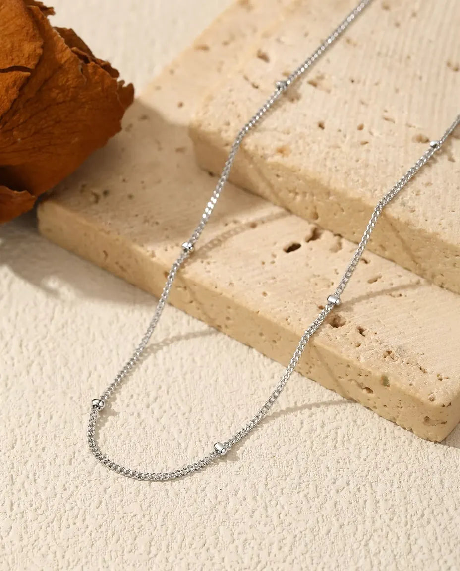 Collier Chaîne Satellite en Argent 925 - posé sur une surface claire près d’une dalle de travertin