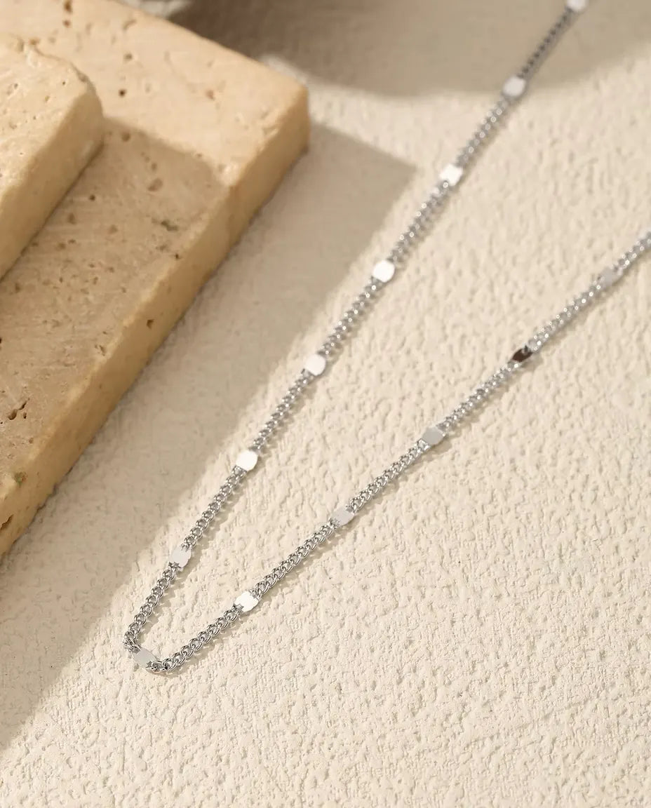 Collier Chaîne à Stations en Argent 925 - posé sur une surface claire près d’une dalle de travertin