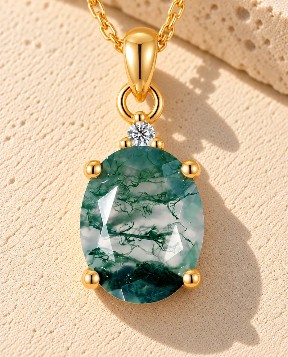 Collier Solitaire Agate Mousse Ovale en Argent 925 Plaqué Or - posé sur une surface claire texturée près d’un bloc de travertin