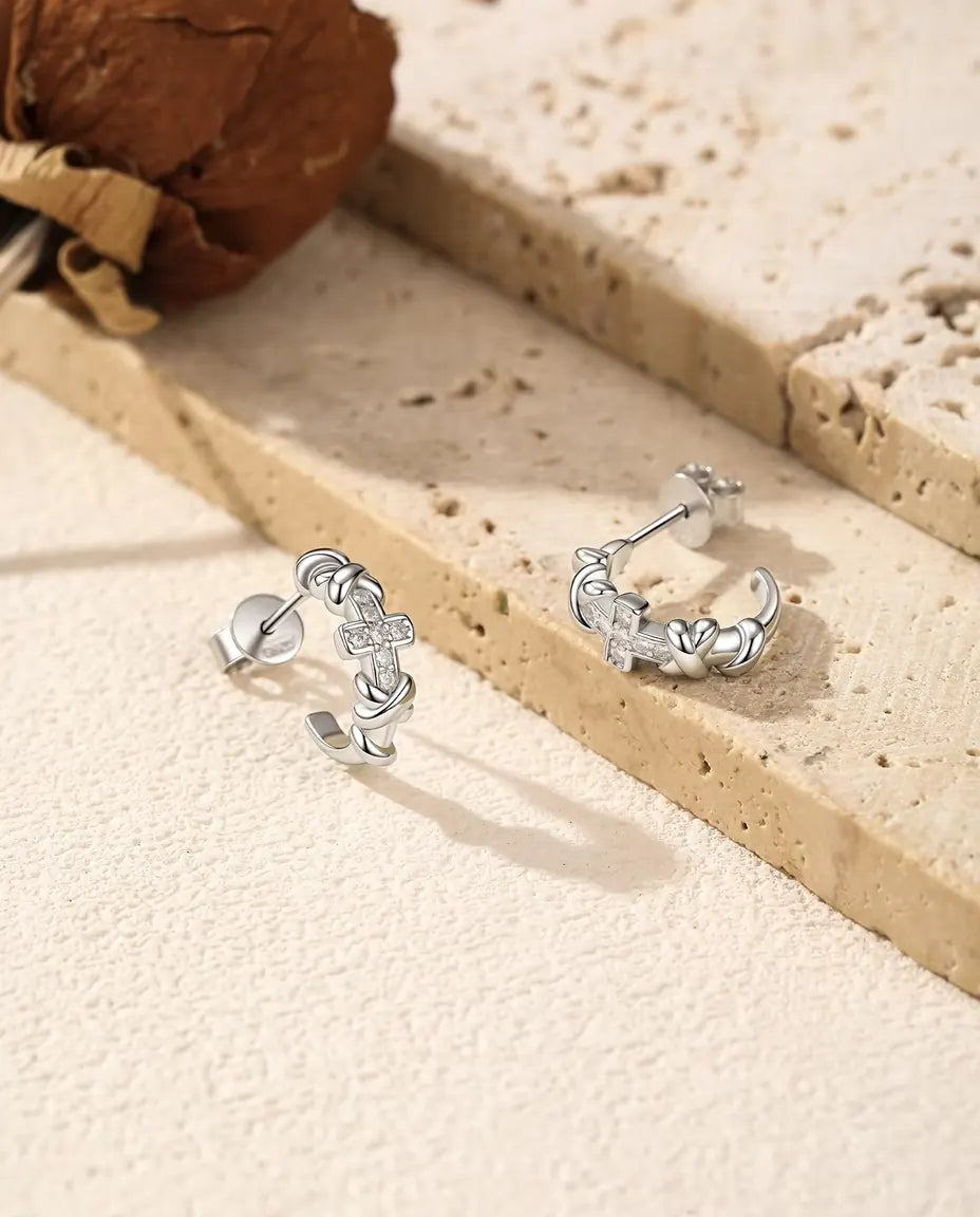 Boucles d’Oreilles Créoles Croix Moissanite en Argent 925 - la paire posée côte à côte sur une surface claire texturée