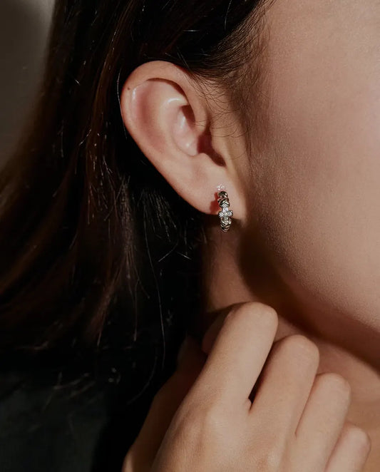 Boucles d’Oreilles Créoles Croix Moissanite en Argent 925 - portées à l’oreille par un mannequin, main près du visage