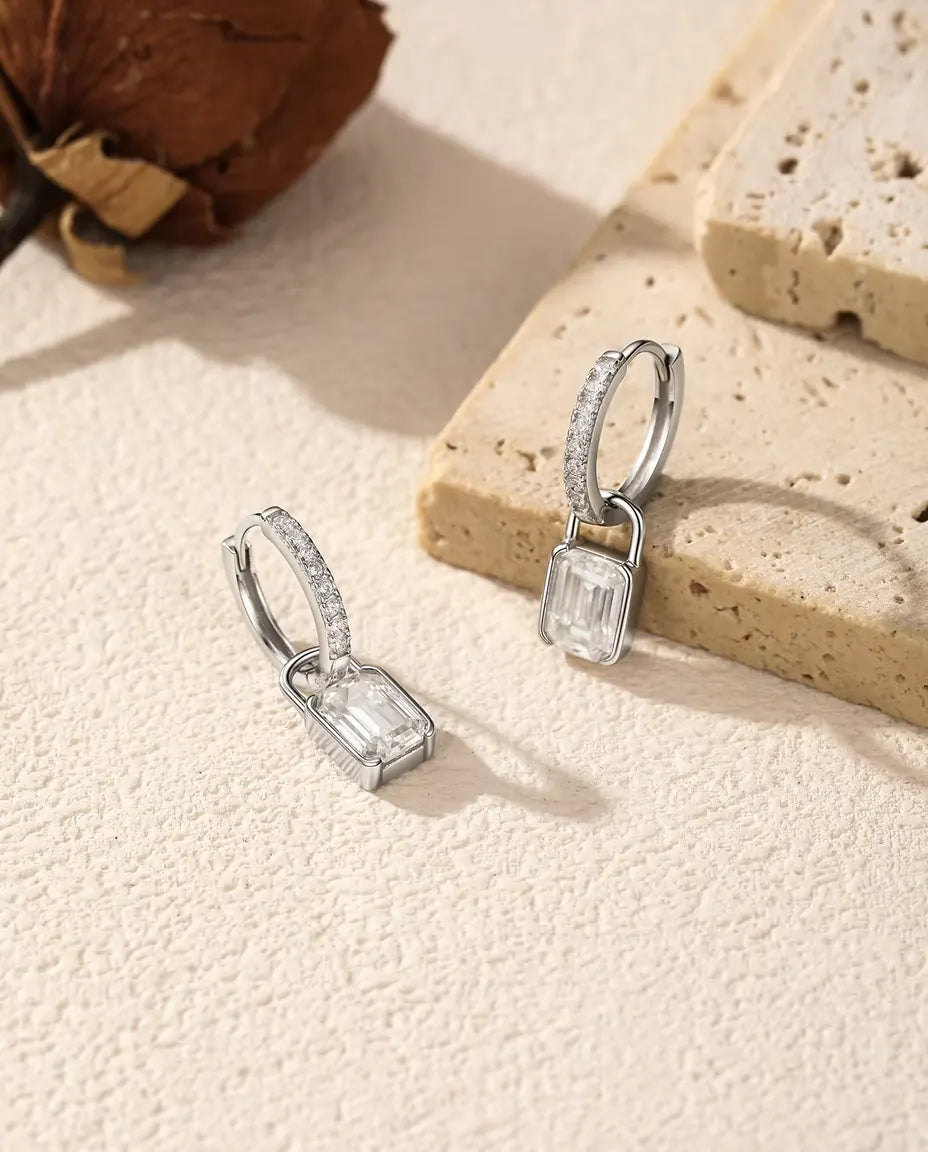 Boucles d’Oreilles Créoles Cadenas Moissanite en Argent 925 - disposées près d’une dalle de travertin
