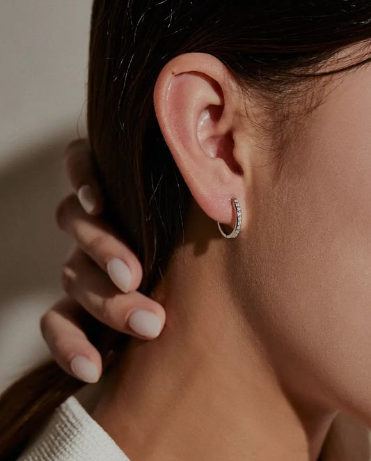 Boucles d’Oreilles Créoles Moissanite en Argent 925 - portées à l’oreille par un mannequin, main retenant ses cheveux