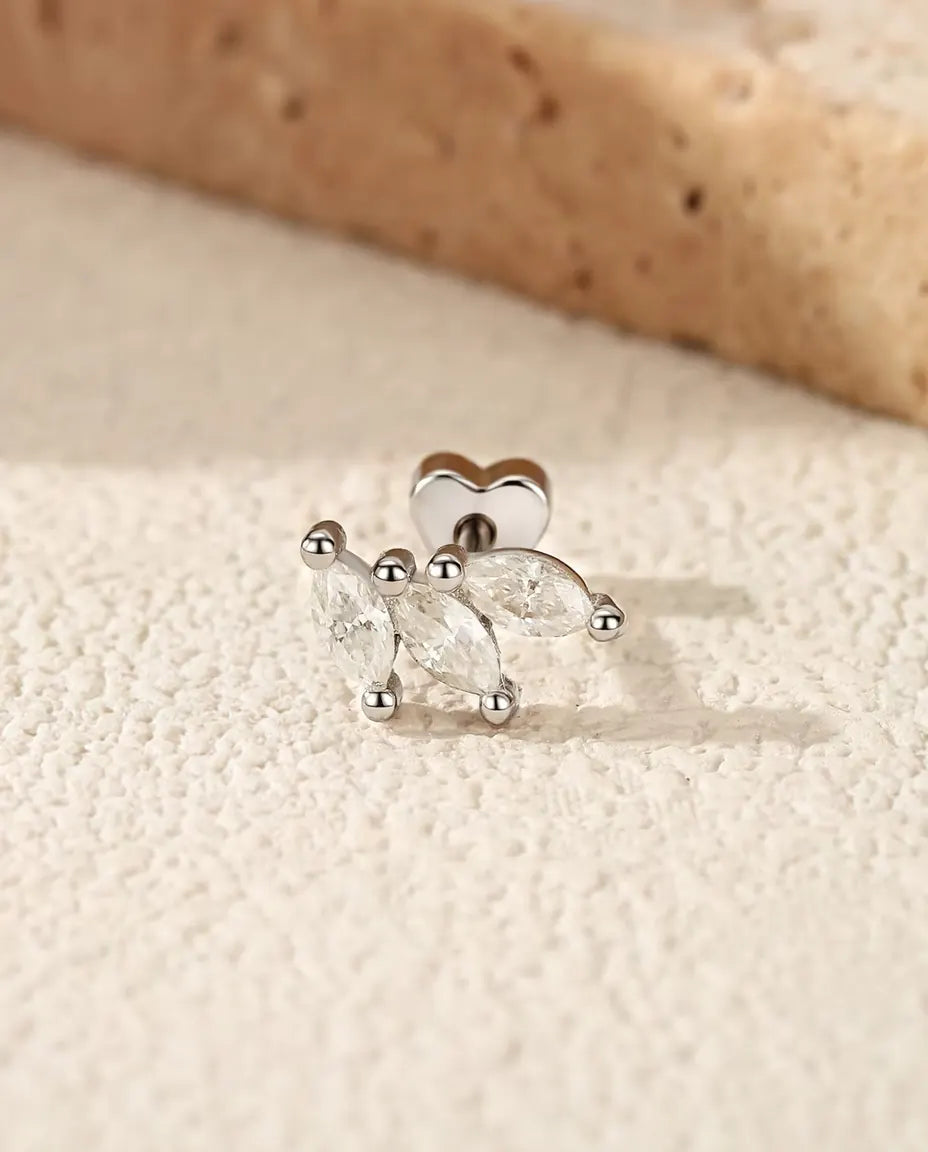 Puces d’Oreilles Feuille Moissanite Marquise en Argent 925 - posée sur une surface claire texturée près d’une dalle de travertin