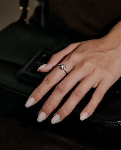 Bague Cœur Moissanite en Argent 925 - portée sur une main posée sur un sac noir