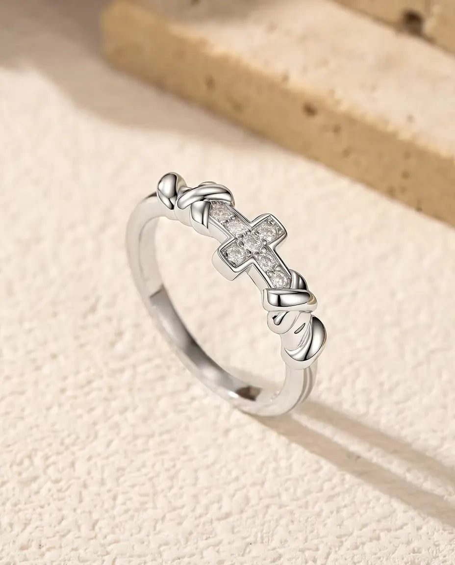 Bague Croix Moissanite en Argent 925 - posée debout sur une surface claire texturée