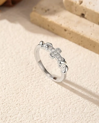 Bague Croix Moissanite en Argent 925 - posée debout près de blocs de travertin, plan plus large