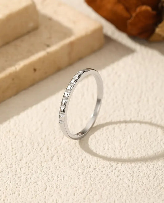 Bague Empilable à Clous en Argent 925 - posée debout sur une surface claire texturée
