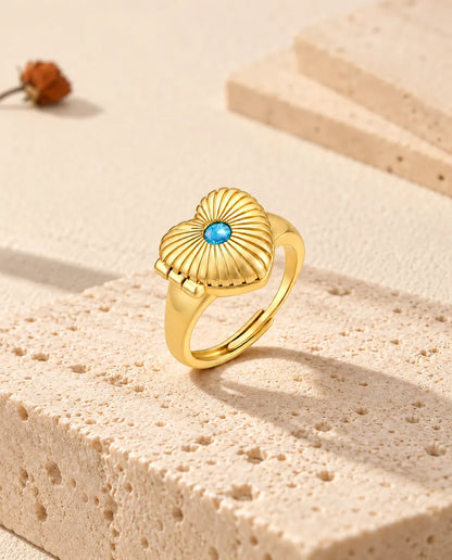 Bague médaillon cœur fermée, posée debout sur un bloc de travertin