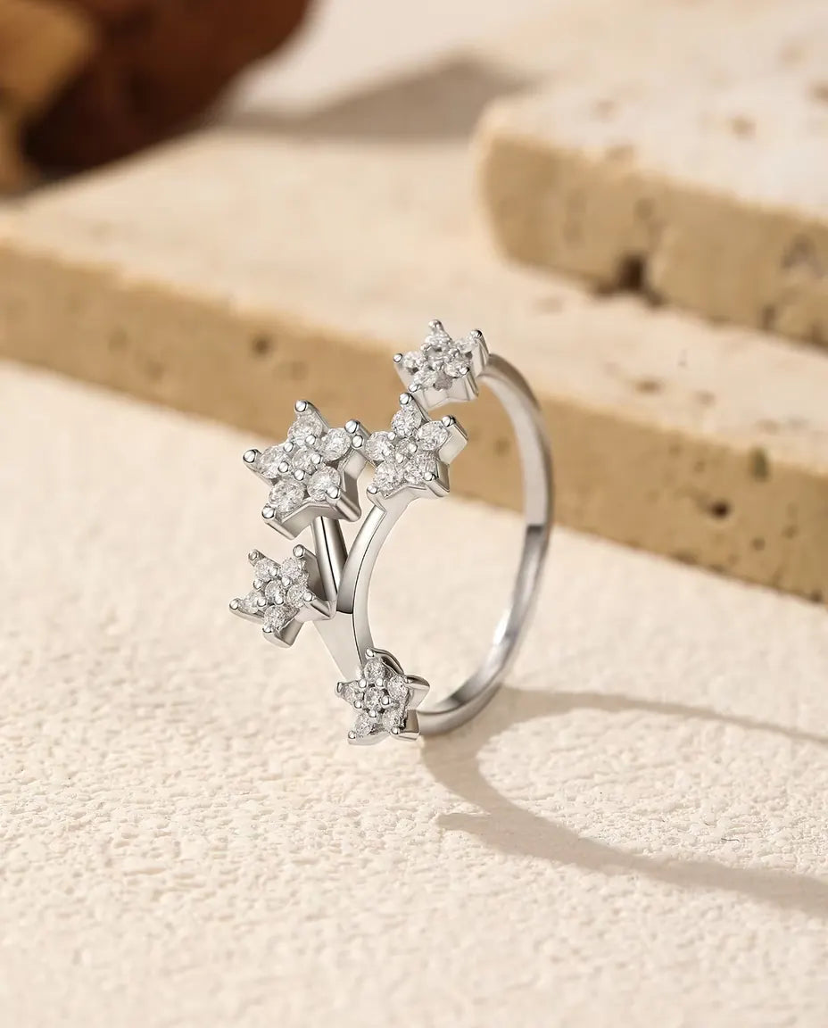 Bague Moissanite Étoiles en Argent 925 - posée debout sur une surface claire texturée