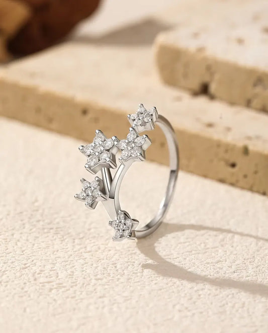 Bague Moissanite Étoiles en Argent 925 - posée debout sur une surface claire texturée