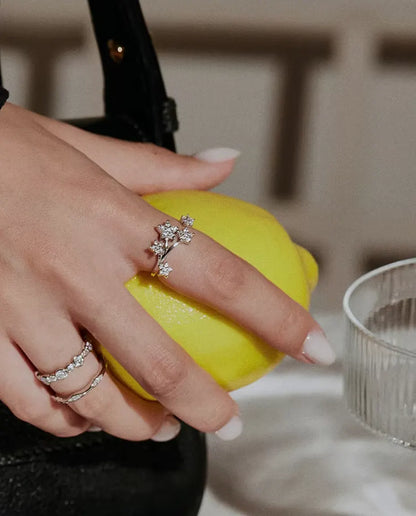 Bague Moissanite Étoiles en Argent 925 - portée avec d’autres bagues, main tenant un citron