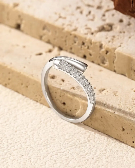 Bague Moissanite Ouverte Croisée en Argent 925 - posée sur le rebord d’une dalle de travertin