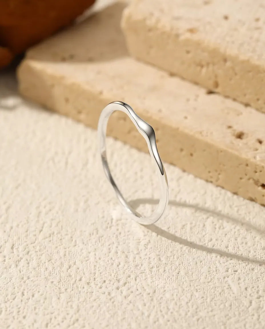 Bague Ondulée Empilable en Argent 925 - posée debout sur une surface claire texturée