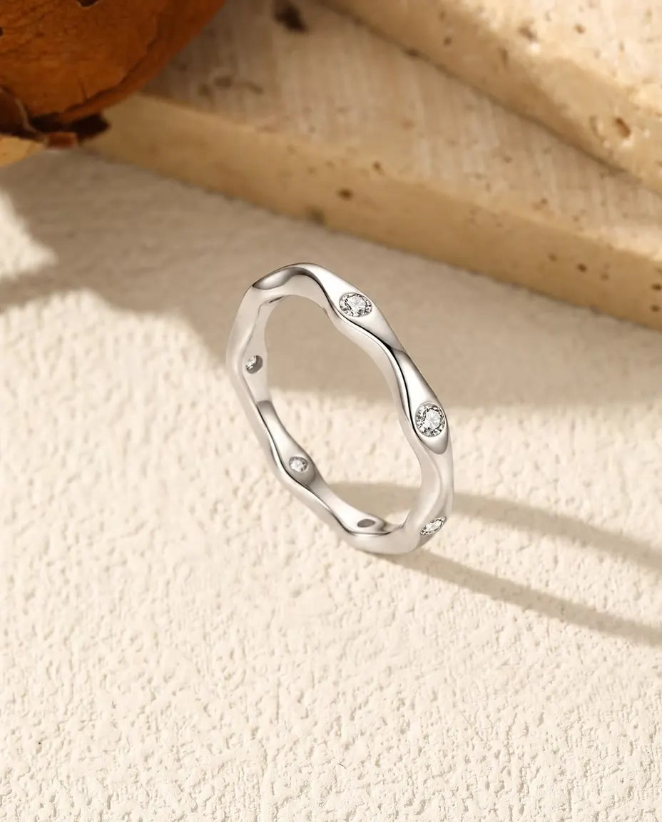 Bague Ondulée Moissanite en Argent 925 - posée debout sur une surface claire texturée