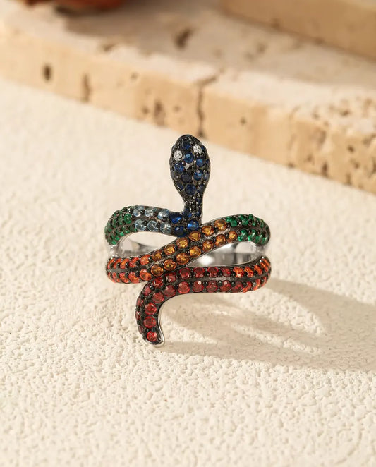 Bague Serpent en Argent 925 aux Pierres Arc-en-ciel - posée debout sur une surface claire texturée