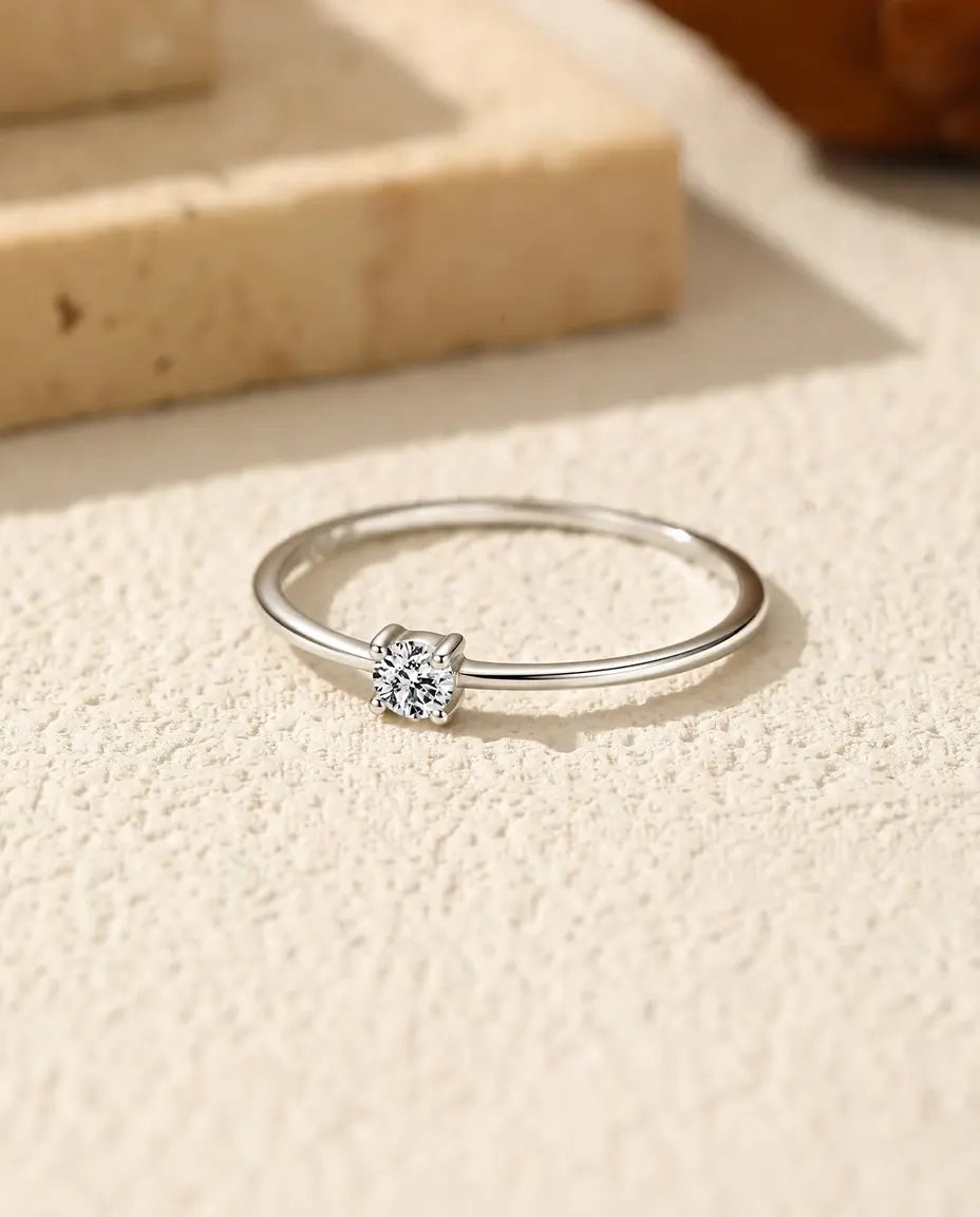 Bague Solitaire Moissanite Fine en Argent 925 - posée à plat sur une surface claire texturée