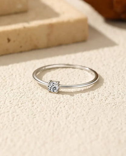 Bague Solitaire Moissanite Fine en Argent 925 - posée à plat sur une surface claire texturée