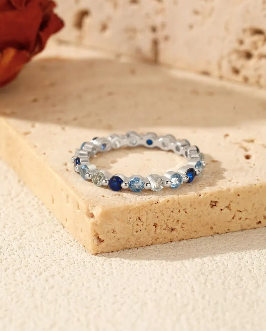 Bague Tour Complet Zircone Bleue en Argent 925 - posée sur un bloc de travertin