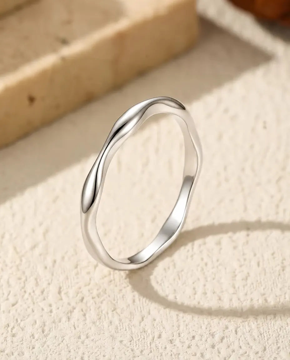 Bague Vague en Argent 925 - posée debout sur une surface claire texturée