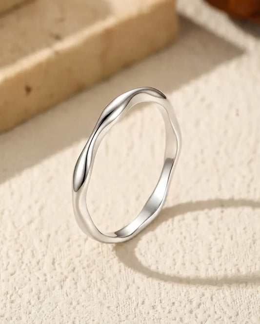 Bague Vague en Argent 925 - posée debout sur une surface claire texturée