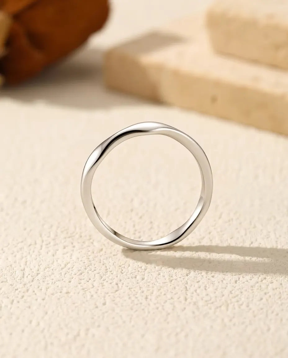 Bague Vague en Argent 925 - vue de face, posée debout sur une surface claire texturée