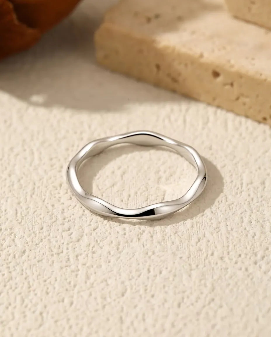 Bague Vague en Argent 925 - posée à plat sur une surface claire texturée