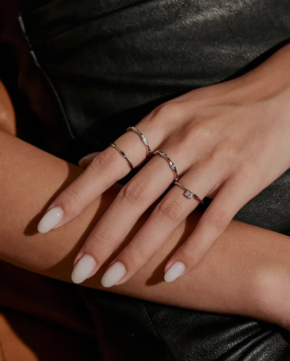 Bague Moissanite Vague en Argent 925 - portée avec d’autres bagues, mains posées l’une sur l’autre