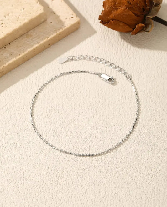 Bracelet Chaîne Diamantée en Argent 925 - posé à plat sur une surface claire texturée, avec fermoir et chaînette d’extension