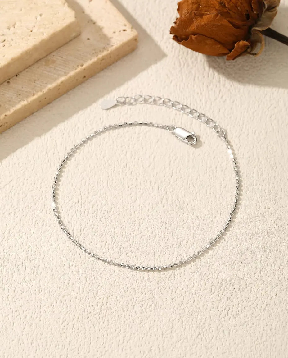 Bracelet Chaîne Diamantée en Argent 925 - posé à plat sur une surface claire texturée, avec fermoir et chaînette d’extension
