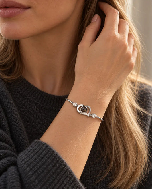 Femme la main dans les cheveux, portant le bracelet cœur ouvert argenté avec photo cachée