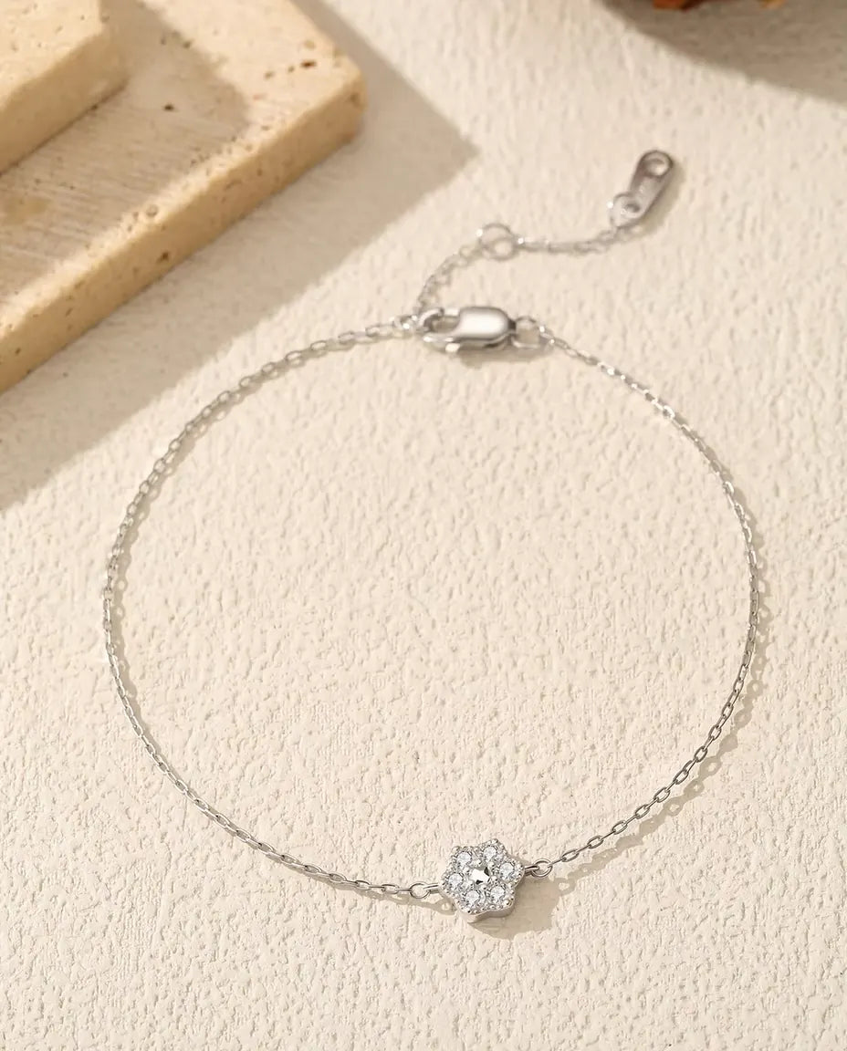 Bracelet Fleur Moissanite en Argent 925 - posé à plat sur une surface claire texturée, avec fermoir et chaînette d’extension