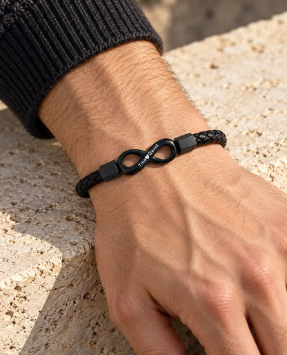 Homme portant le bracelet infini gravé noir en similicuir au poignet, avec un pull en maille anthracite
