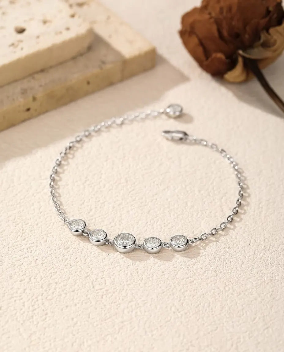 Bracelet Moissanite Serti Clos en Argent 925 - posé librement sur une surface claire, avec fermoir et chaînette d’extension