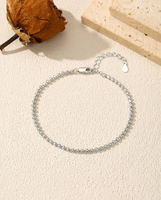 Bracelet Perles Facettées en Argent 925 - posé à plat sur une surface claire texturée, avec fermoir et chaînette d’extension