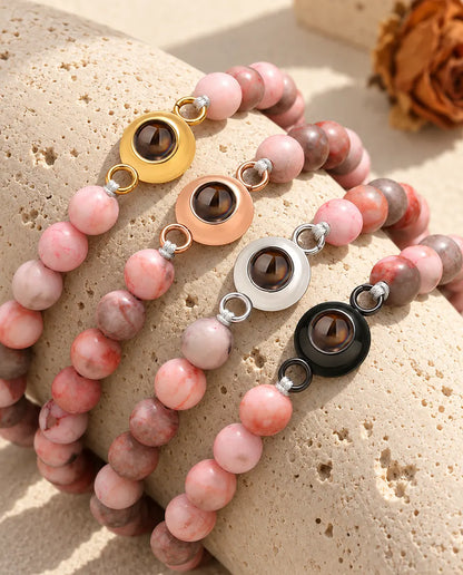 Bracelets de perles rose moucheté dans chaque couleur de charm sur du travertin