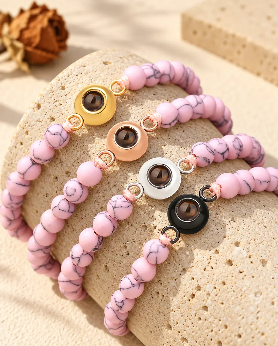 Bracelets de perles rose marbré avec quatre couleurs de charm sur un bloc de travertin