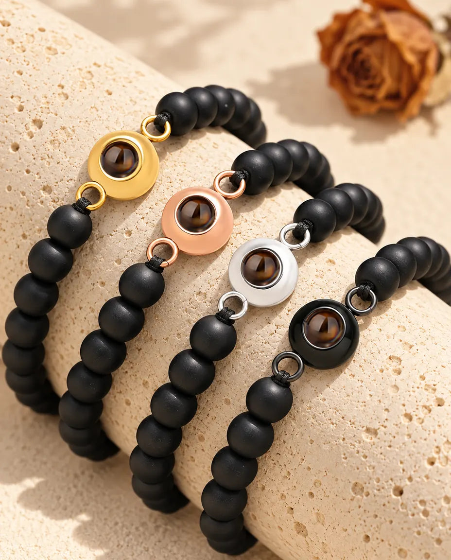 Bracelets de perles noir mat dans chaque couleur de charm sur un bloc de travertin