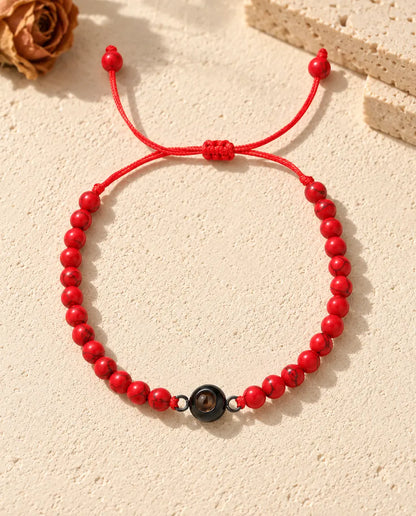 Vue de dessus du bracelet de perles rouges avec anneau noir et nœud coulissant