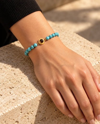 Femme portant le bracelet de perles bleu marbré avec charm doré au poignet