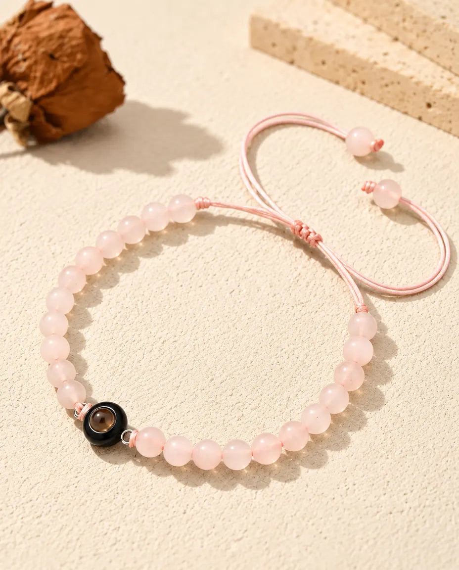 Bracelet de perles rose poudré avec anneau noir sur du plâtre clair
