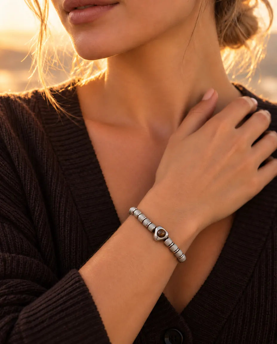 Femme la main sur la clavicule, portant le bracelet de perles argenté à perle cœur